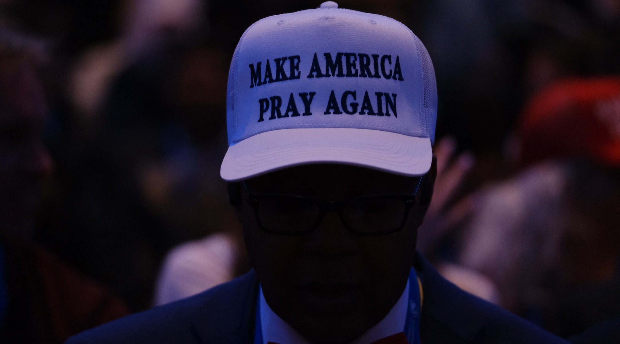 A man wears a hat that says "Make America Pray Again"