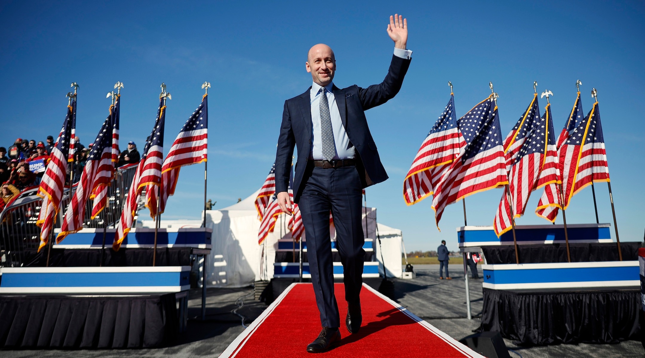 Miller waves to a crowd, flanked by U.S. flags