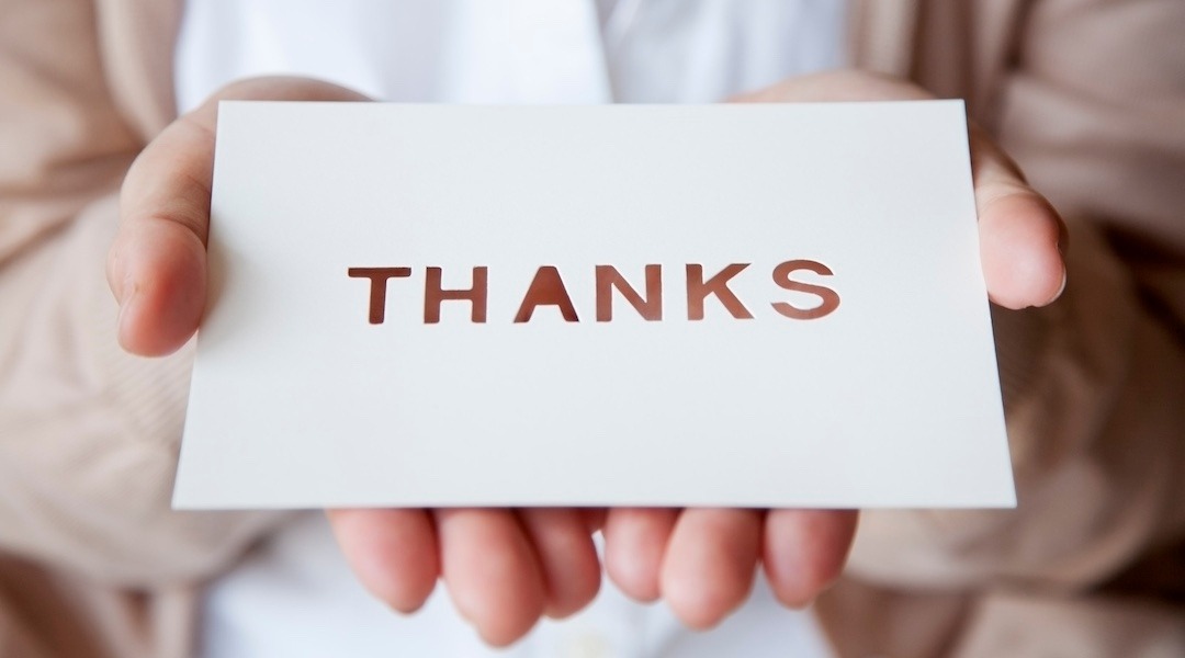 a person holds out a card that says "Thanks" on it