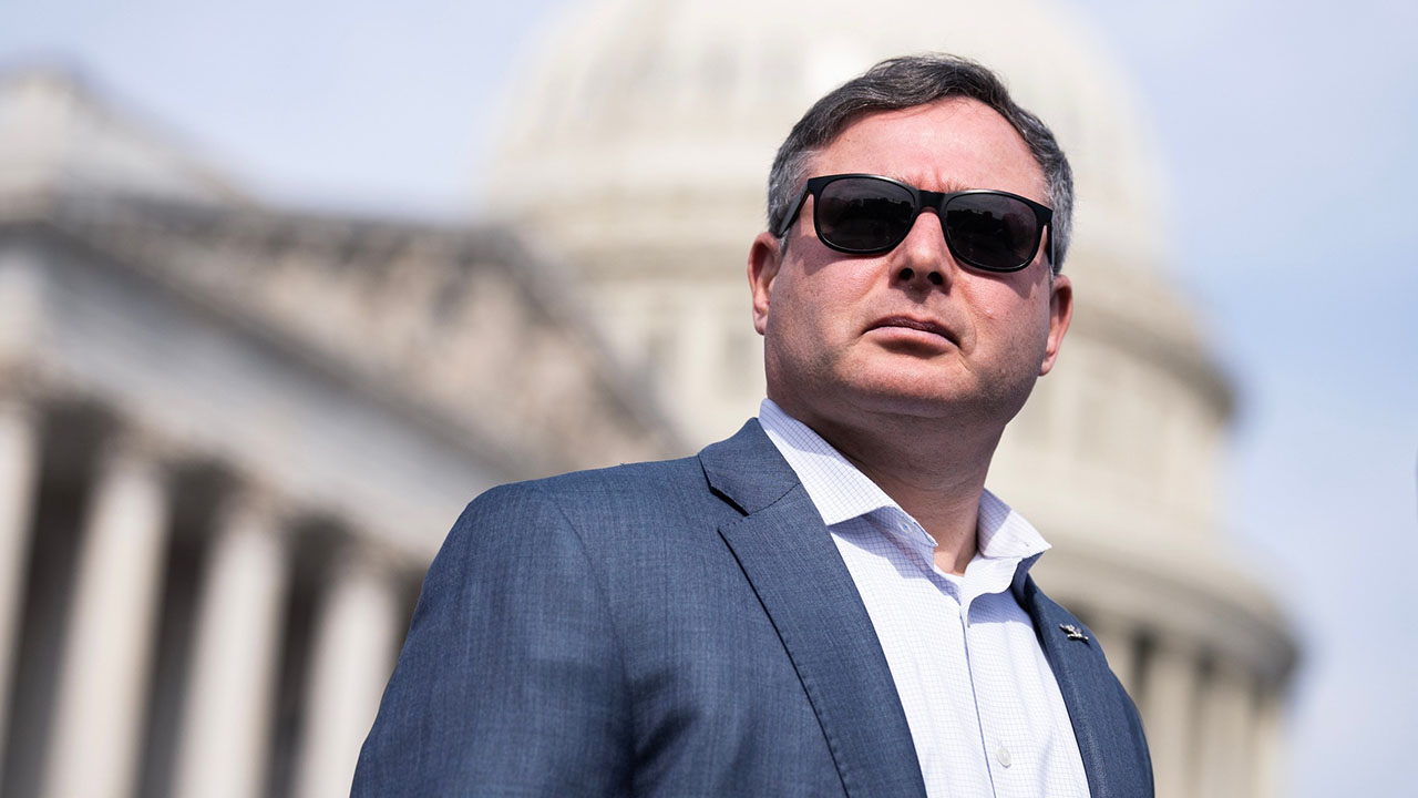 A man in sunglasses stands in front of the capitol