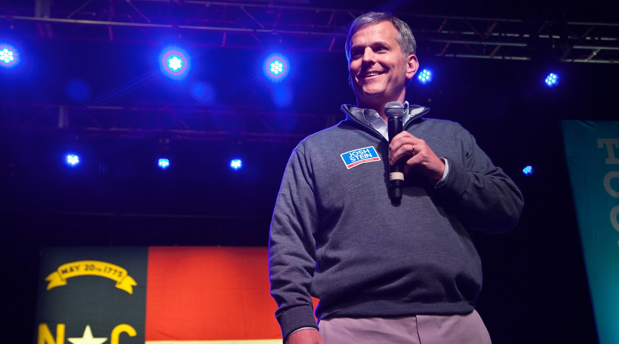 A man speaks into a microphone on stage