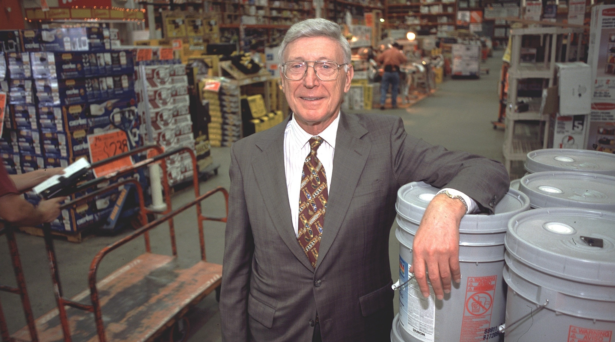 A grey haired man in a suit stands in a Home Depot store
