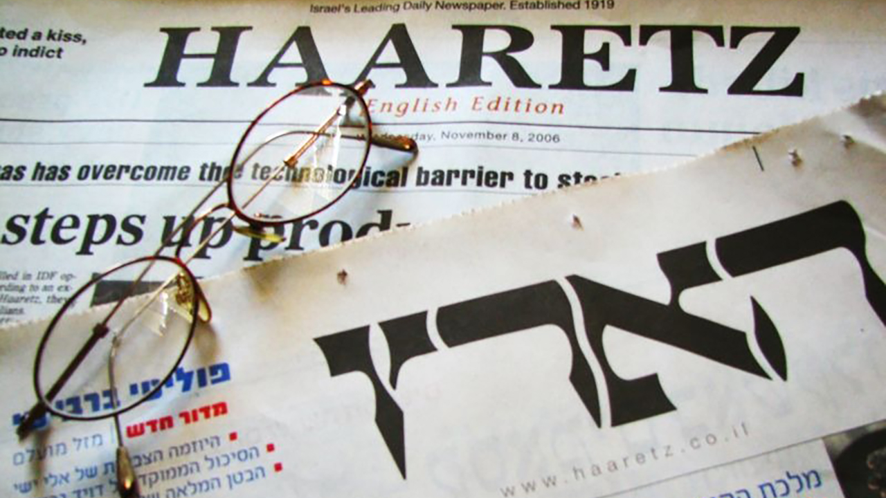 a Hebrew and an English edition of Haaretz sit on a table