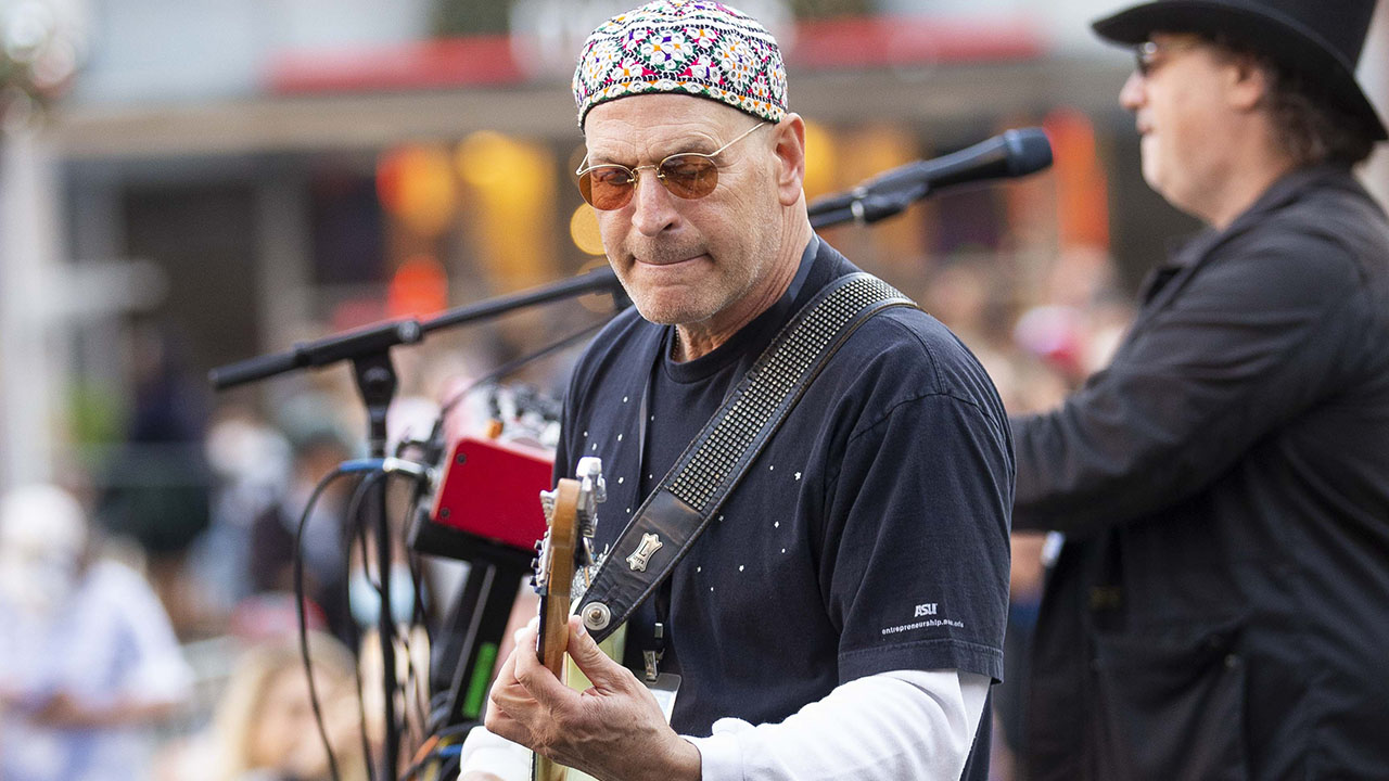a man in a large colorful kippah plays guitar on stage