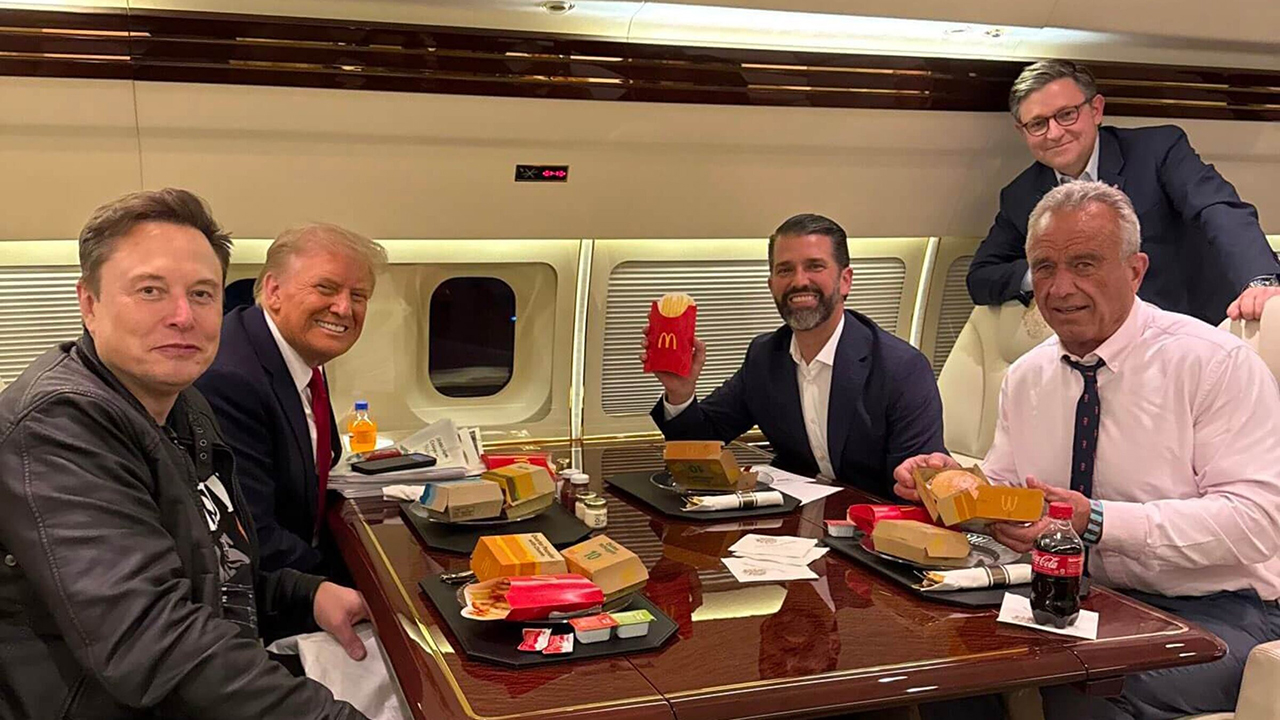 Trump, Musk, Don Jr and RFK smile while holding up McDonald's food on an airplane