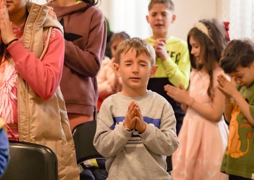 group of children in prayer at indoor event