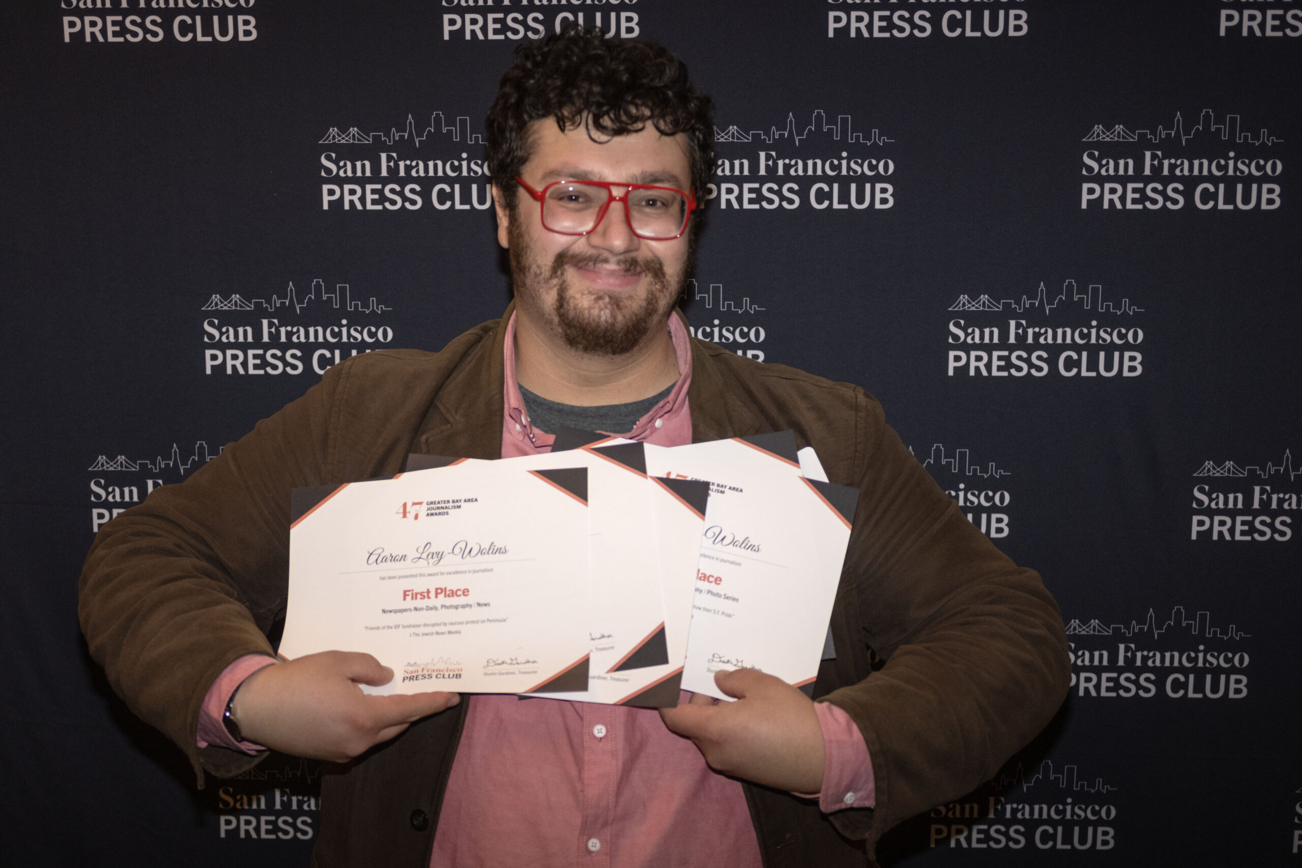 Staff photographer Aaron Levy-Wolins shows off his awards at the 47th annual Greater Bay Area Journalism Awards at the Julia Morgan Ballroom in San Francisco on Wednesday, Dec. 4, 2024. (Emma Goss/J. Staff)