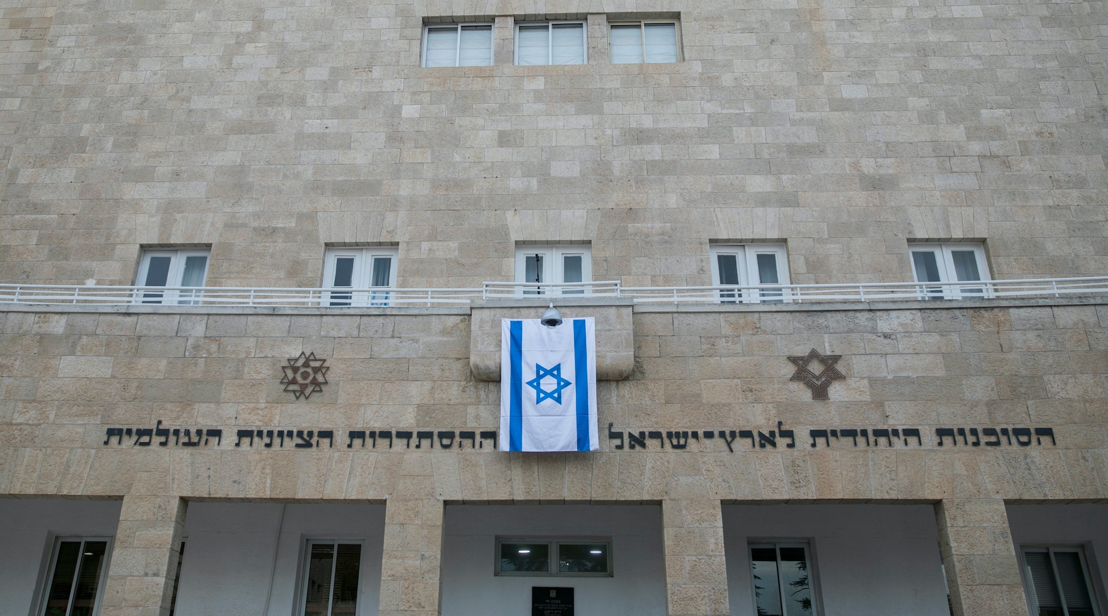 a limestone building with an israeli flag hanging from the front