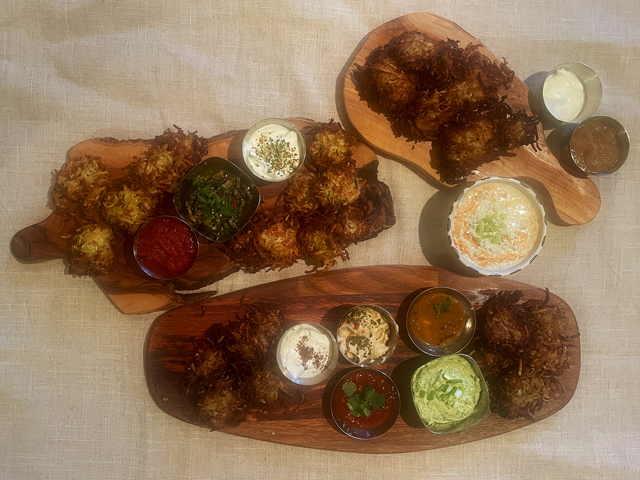 This latke board includes traditional, Italian-style and Mideast-flavored latkes, as well as a Buffalo dip, a chopped-olive dip and a cilantro tahini sauce. (Faith Kramer)