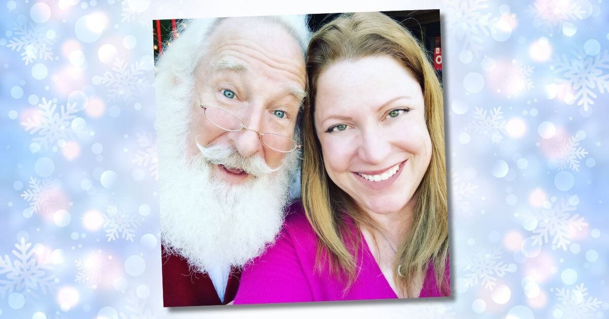 a smiling blonde woman takes a selfie with a man dressed as Santa
