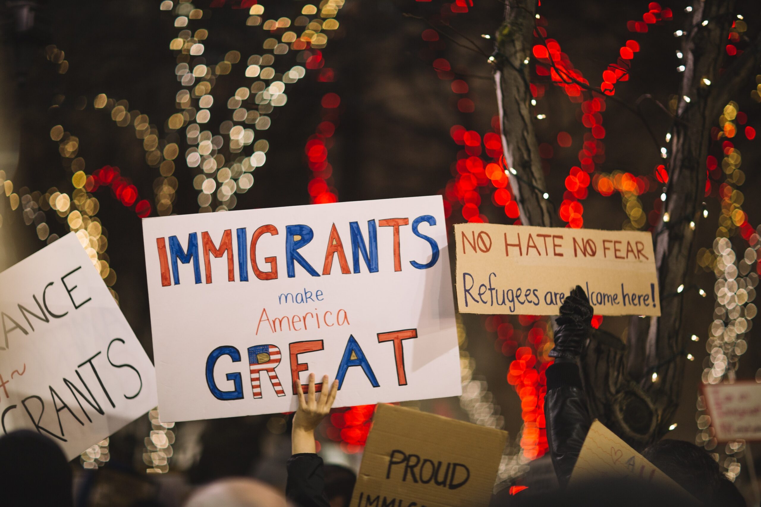 a person holds up a sign that says "Immigrants make American great"