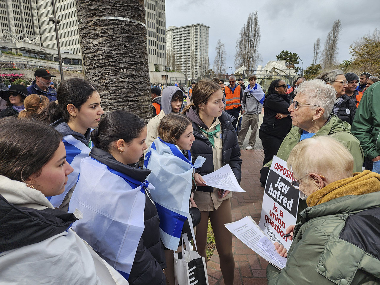 Socialist Workers Part member Maggie Trowe (right), whose sign reads “Opposing Jew-Hatred is a union question," speaks with Girl Scouts at a Jewish unity march in San Francisco on March 3, 2024. (Courtesy)