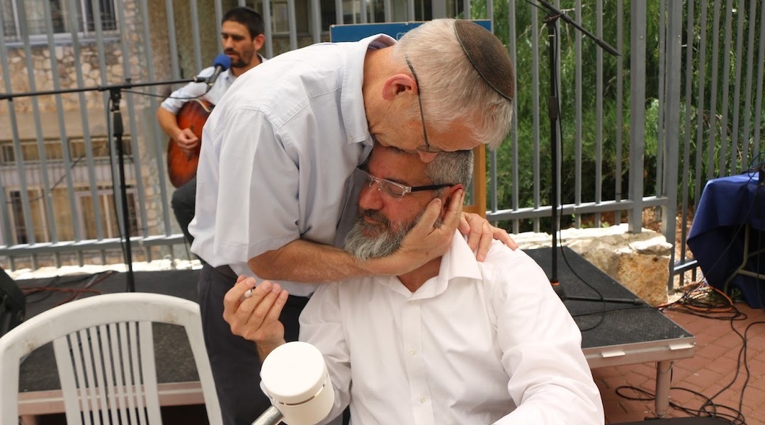 Two grey-haired men hug