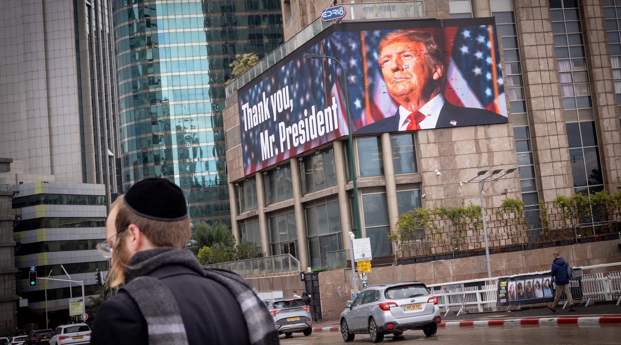 A man walks past a large billboard with a picture of Trump and the words "Thanks you, Mr. President"