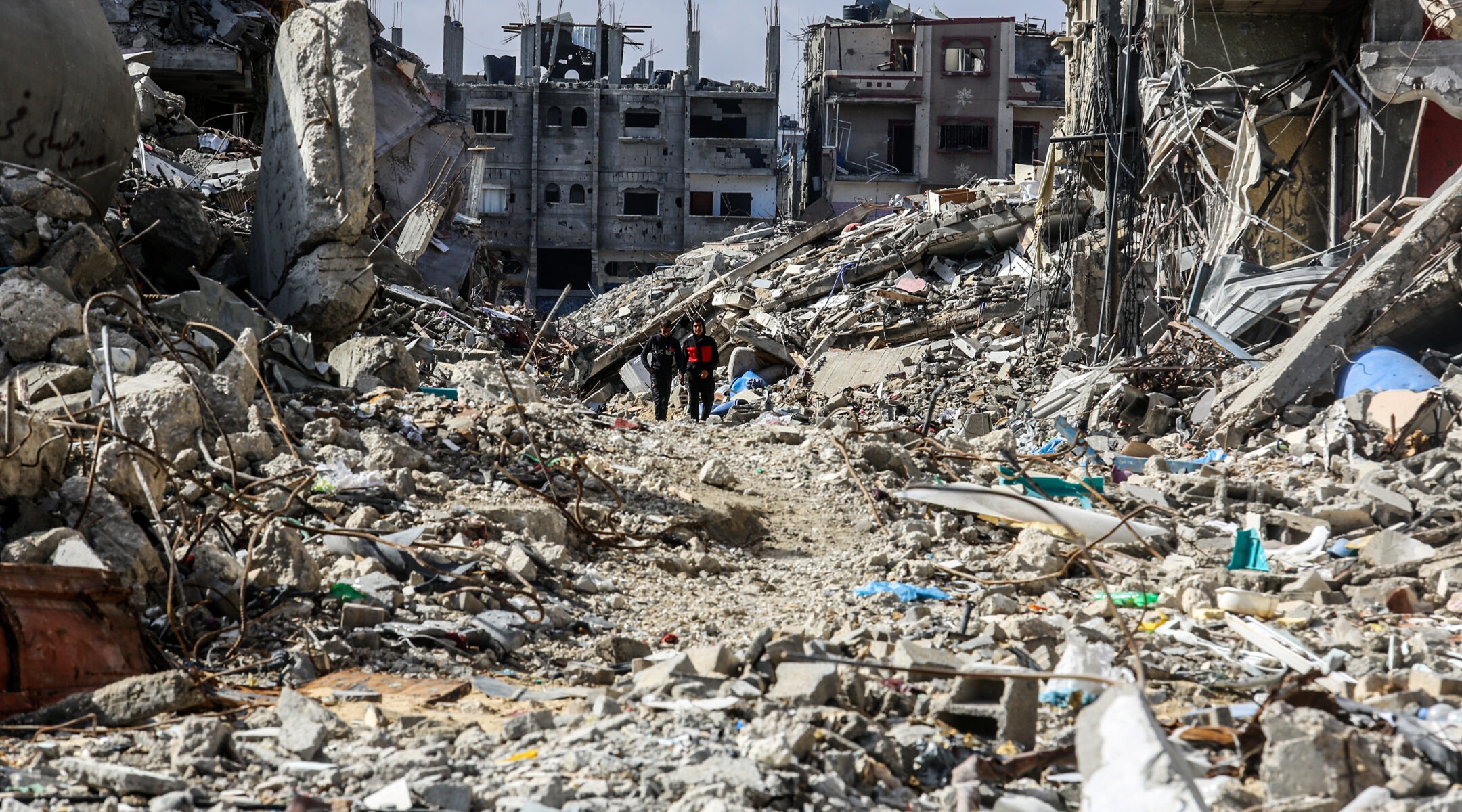 People walk through a large urban area reduces to rubble