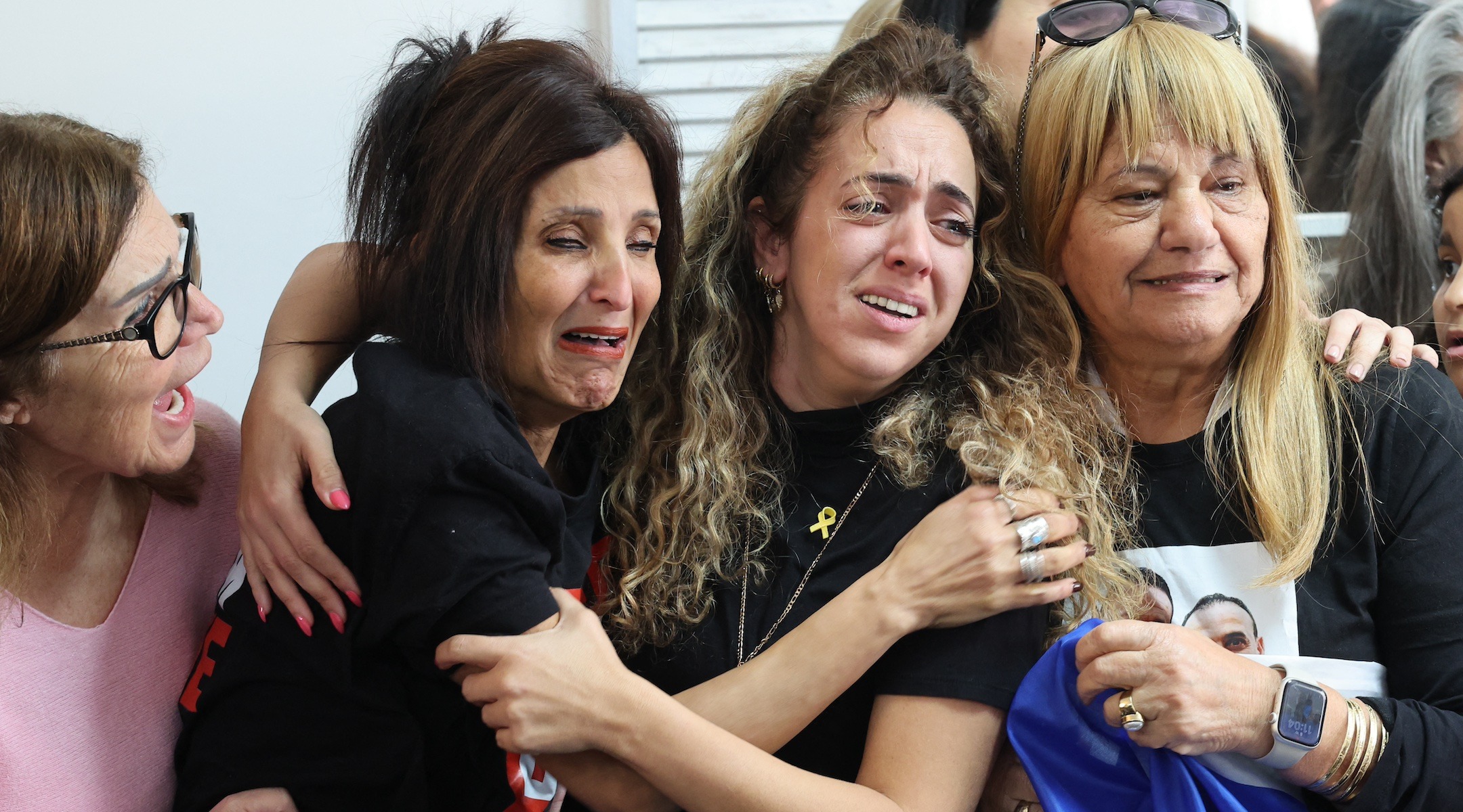 Four women weep openly and hug each other