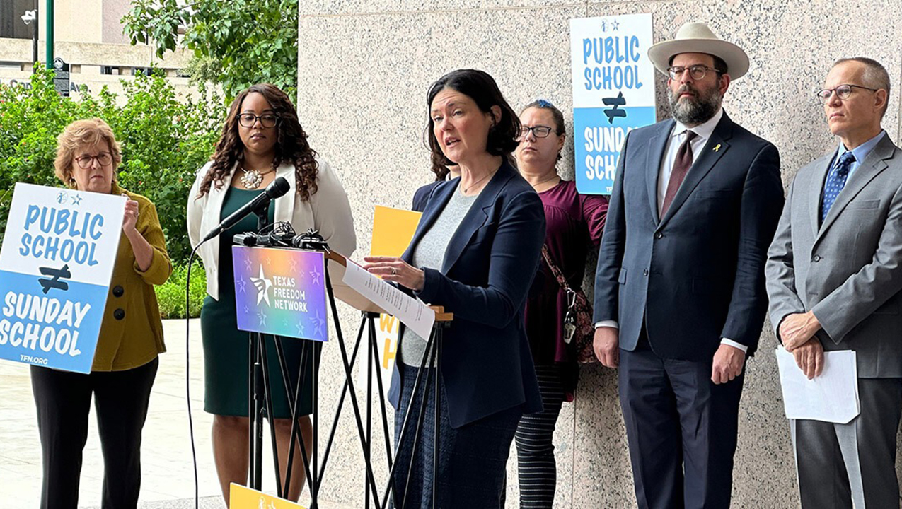 Amanda Tyler of the Baptist Joint Committee for Religious Liberty speaks at a press conference outside a hearing of the Texas State Board of Education on adopting a Bible-infused curriculum for public schools. Rabbi Neil Blumofe is in the back, wearing a hat. (Forward/Courtesy of Texas Freedom Network)