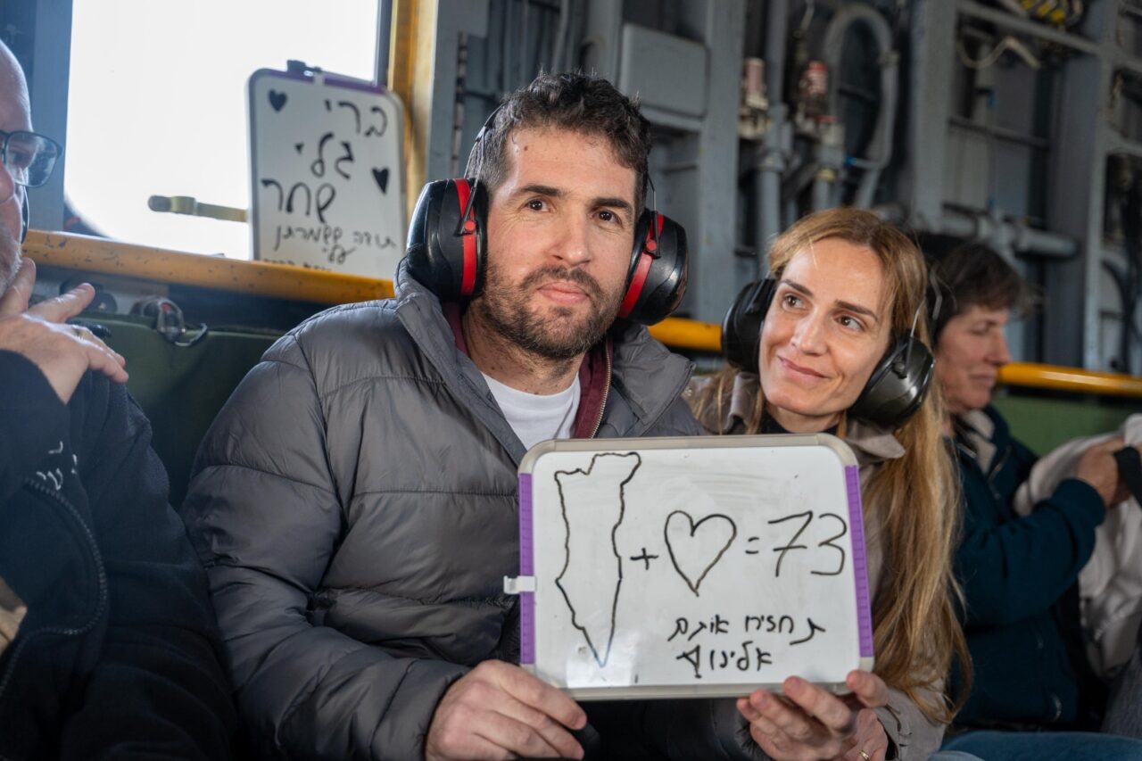 On his helicopter ride to an Israeli hospital on Saturday, newly freed hostage Sagui Dekel-Chen showed his support for the remaining 73 hostages, as his wife, Avital Dekel-Chen, looks on.  (Israel Government Press Office)