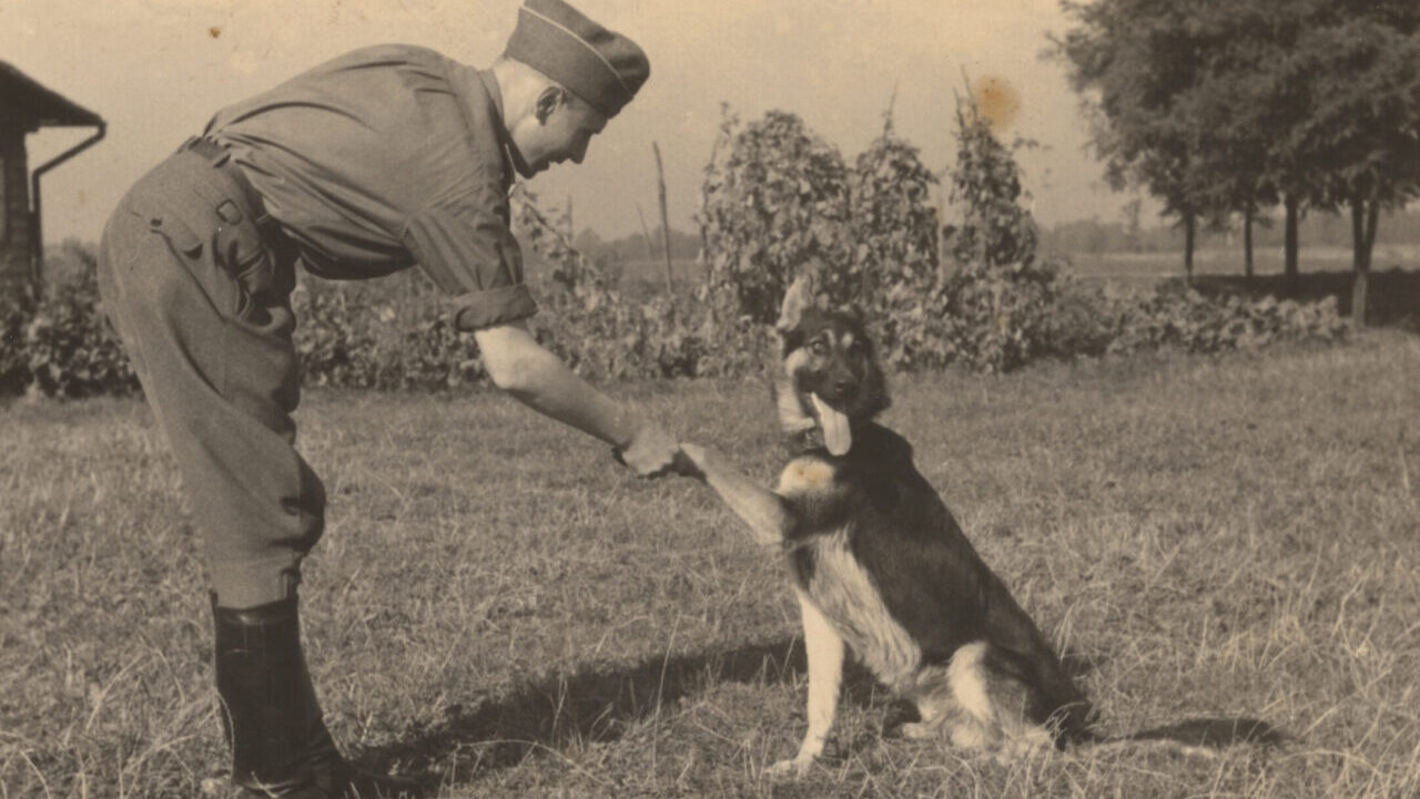 An SS officer shakes a dog’s paw. (Courtesy U.S. Holocaust Memorial Museum)