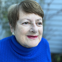 An older woman smiles slightly in a blue sweater