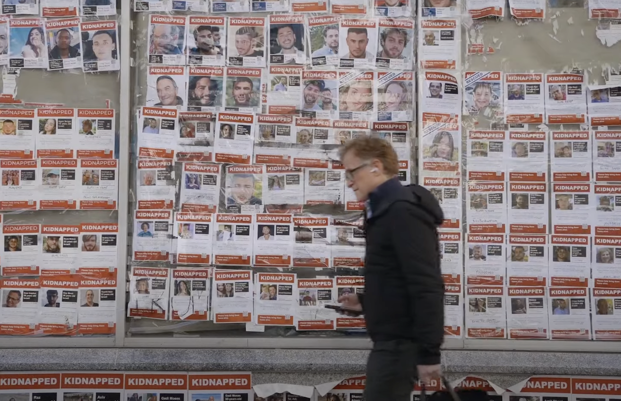 A man walks past a wall of hostage poster, some which have been torn down. "Torn" is a look at the way the posters became a flashpoint in the U.S. (Screenshot)