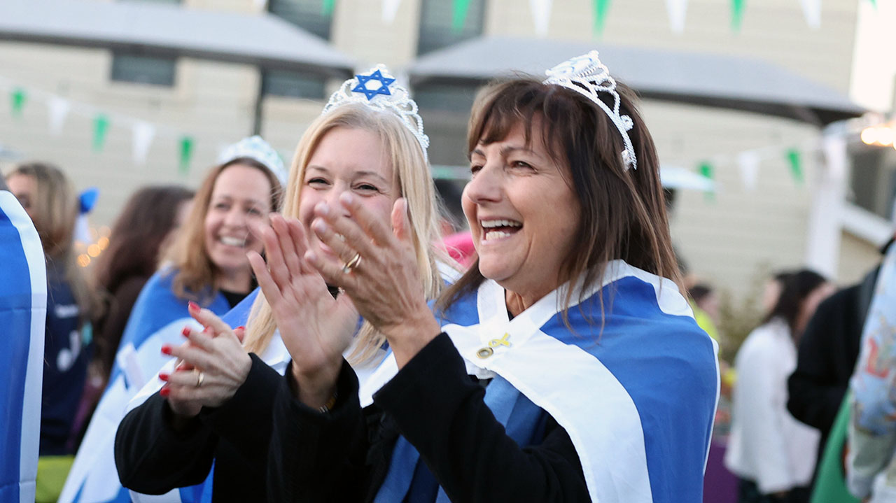 Oshman Family JCC Israel Cultural Connection senior director Ronit Jacobs (right) wears a crown and an Israeli flag during at a JCC fundraising event in March. (OFJCC)