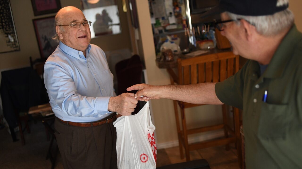 Holocaust survivor Rudi Jocobsen, left, takes a bag of food from Uriel Rauff, who works for Jewish Family Service Colorado as a driver for the kosher Meals on Wheels Program in Denver, Colorado, on December 19, 2017. (RJ Sangosti/The Denver Post via Getty Images)
