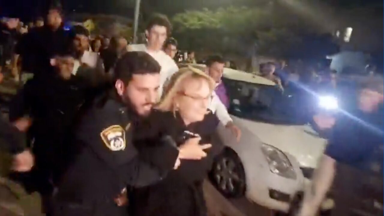 A woman is escorted by police officers away from a group of protesters at an Israeli-Palestinian memorial event at a Reform synagogue in Raanana, Israel on April 29, 2025. (Screenshot)