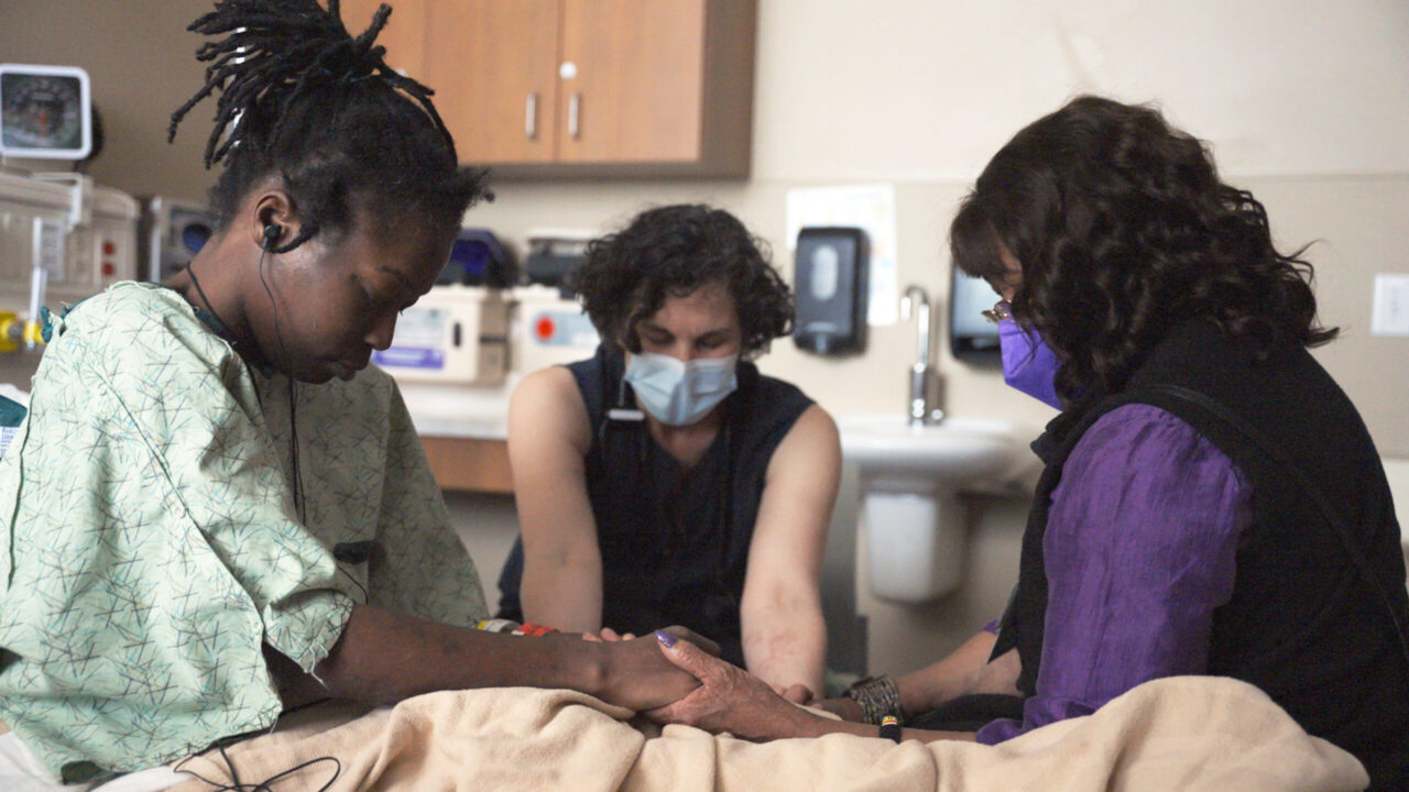 Naomi Thomas, Dr. Jessica Zitter and Chaplain Betty Clark share a moment of prayer.  (Reel Medicine Media)