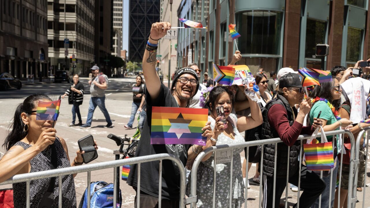 An attendee of the 2025 S.F. Pride Parade holds up a flag distributed by A Wider Bridge. (Aaron Levy-Wolins/J. Staff)