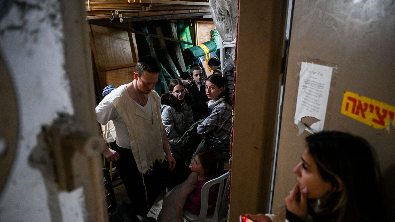 People take cover in a stairway in Jerusalem, as a red alert is sounded when drones and missiles fired from Iran neared Israel, April 14, 2024. (Arie Leib Abrams/Flash90)