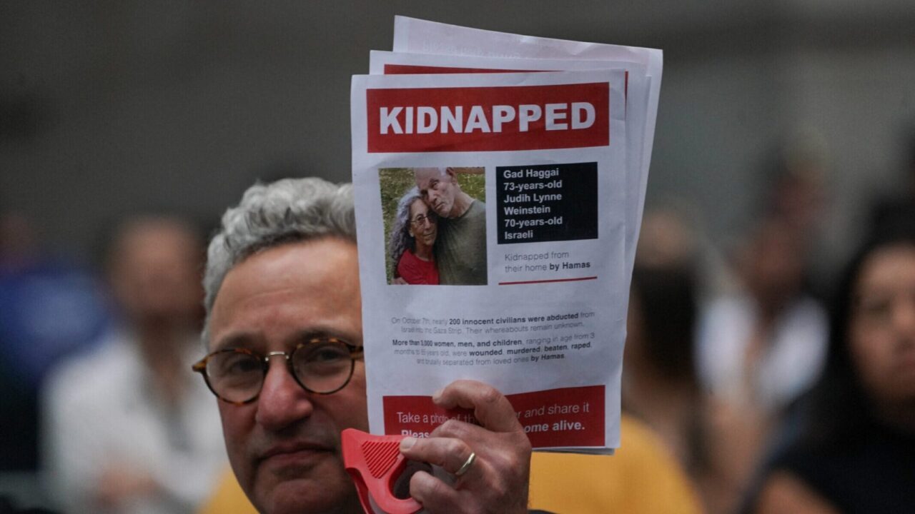 A man holds a picture of kidnapped American-Israeli hostages Gad Haggai and Judith Lynne Weinstein during a rally outside the New York Stock Exchange on Oct. 26, 2023. (Bryan R. Smith/AFP via Getty Images)