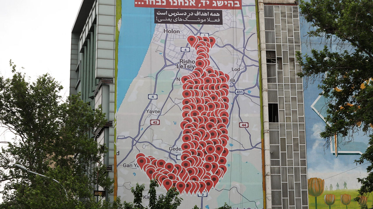 People drive past an anti-Israel billboard featuring the shape of a traditional Yemeni dagger made of map pins and sentences reading "All targets are within reach" in Hebrew and "All targets are available, now Yemeni missiles" in Persian, in Tehran's Palestine square on May 5, 2025. (Atta Kenare/AFP via Getty Images)