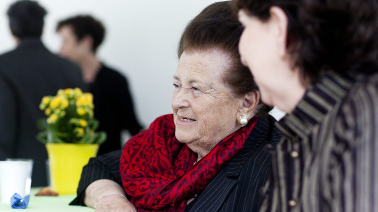 Tauba Weiss (left) sits with Jewish Family and Children's Services executive director Anita Friedman at a Yom HaShoah community commemoration in San Francisco in the 2010s. (Courtesy JFCS Holocaust Center)