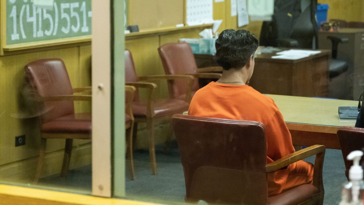 man in orange jumpsuit sits in court