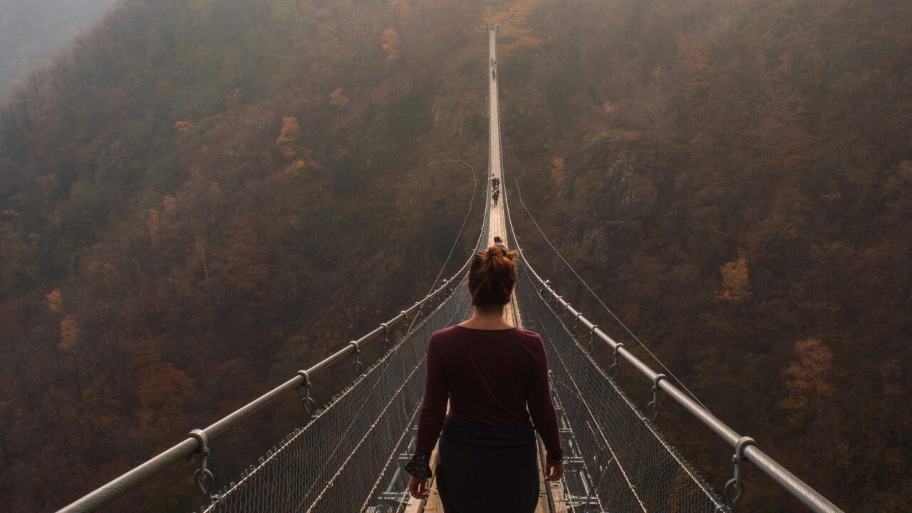 woman walks across suspended footbridge