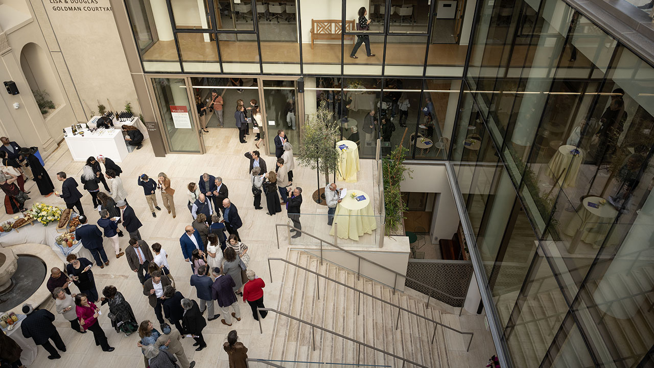 People mingle in the remodeled courtyard of Congregation Emanu-El in San Francisco during a reception celebrating the building's reopening, Sept. 12, 2025. The main sanctuary is to the left of the frame, while the stairs on the right lead down to the main entrance. (Aaron Levy-Wolins/J. Staff)
