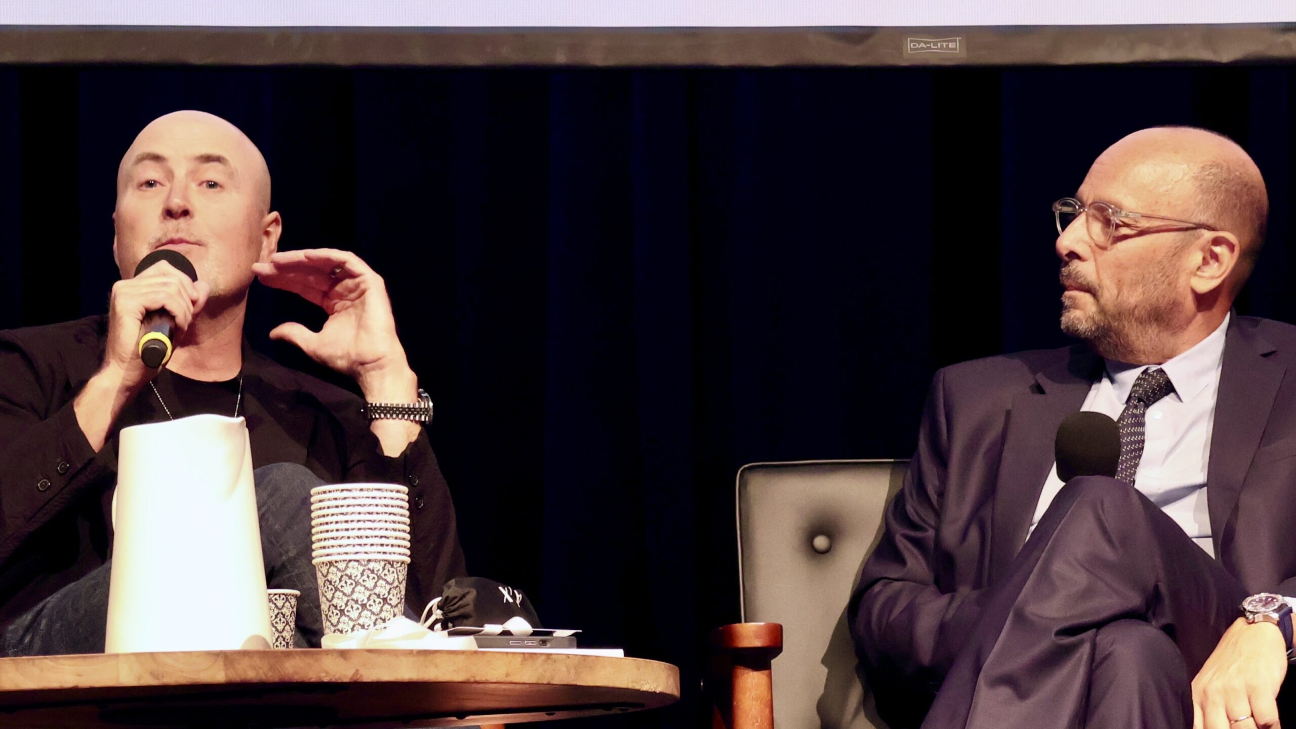 Two men talk on conference stage