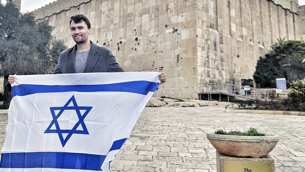 Charlie Kirk holds an Israeli flag outside the Cave of the Patriarchs in the West Bank. (Itamar Ben-Gvir/X)