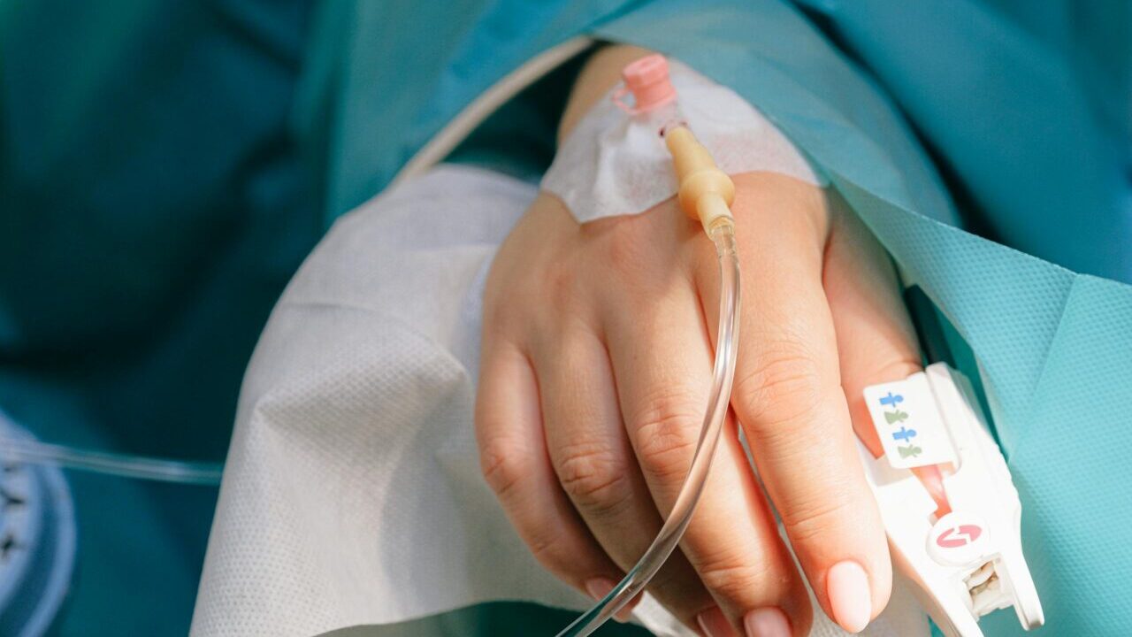 Close-up of a patient's hand with intravenous therapy and pulse oximeter