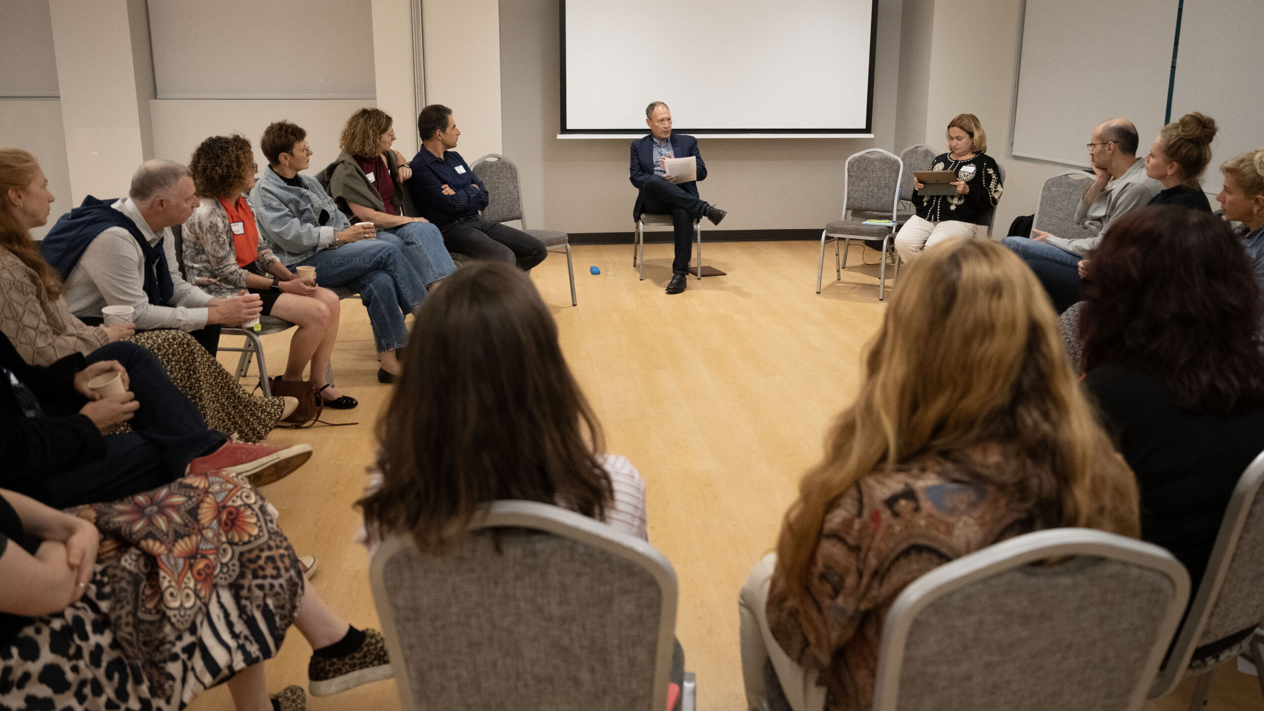 Adults sitting in circle listen to speaker