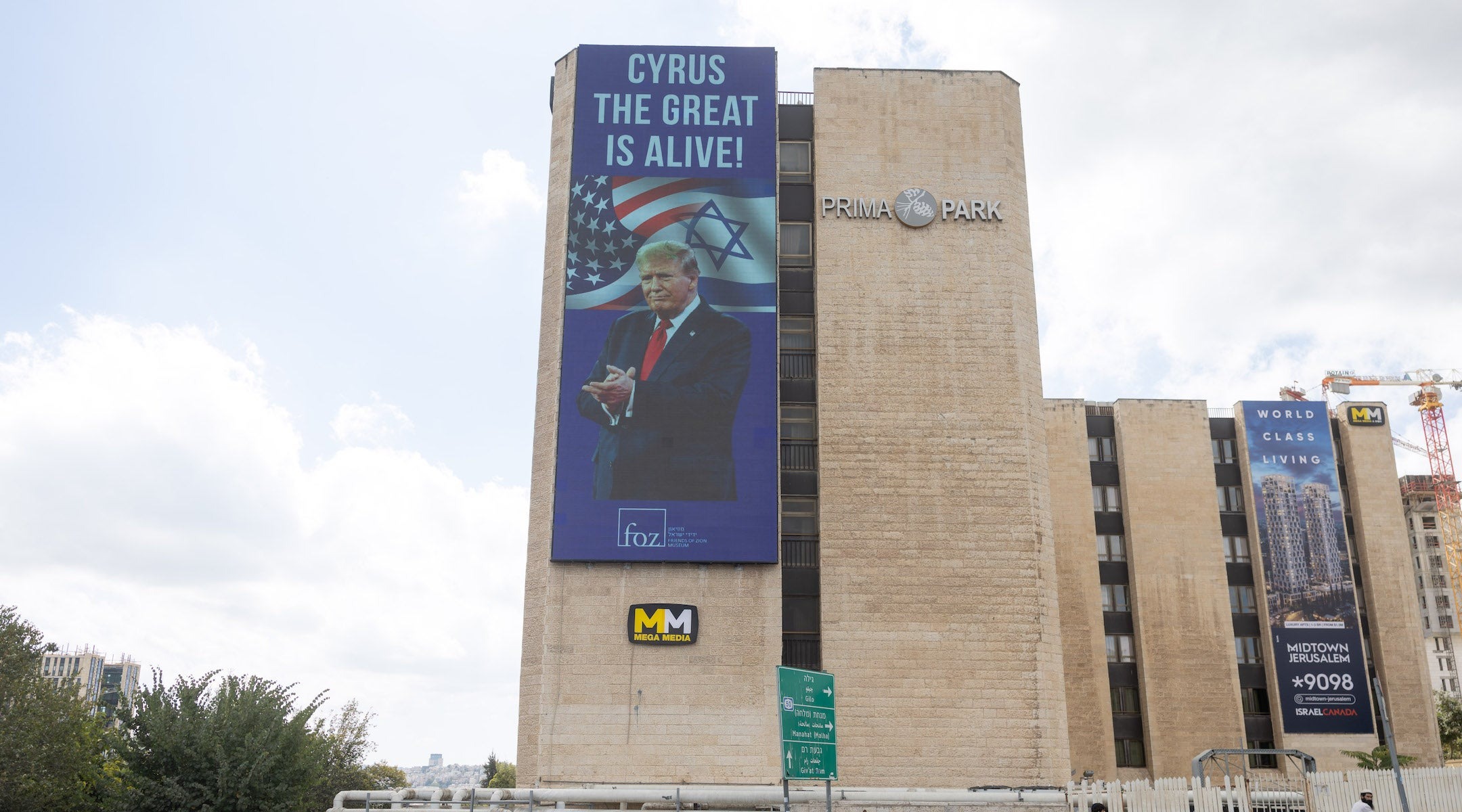 People walk next to a sign honouring U.S. President Donald Trump, in central Jerusalem, Oct. 10, 2025. (Chaim Goldberg/Flash90)