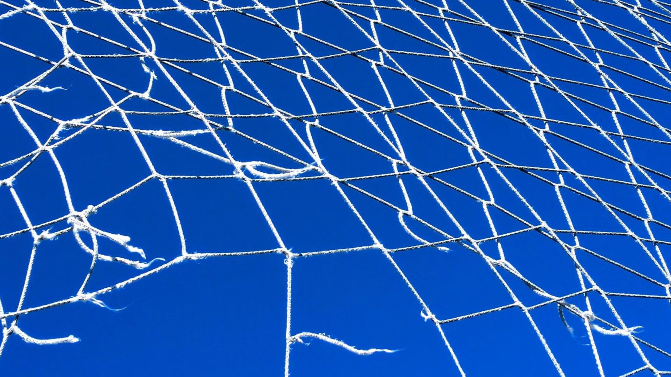Broken tall safety net hanging, clear blue sky, full frame view suitable for background purposes. Galicia, Spain.