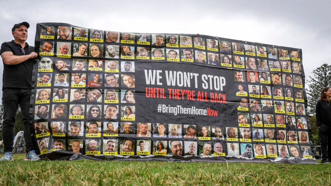 Members of the Australian Jewish community hold a banner bearing the portraits of Israelis held hostage in the Gaza Strip by Palestinian militants during a rally in Sydney on Oct 7, 2025, to mark the two-year anniversary of the attack by Hamas on Israel. (David Gray/AFP via Getty Images)