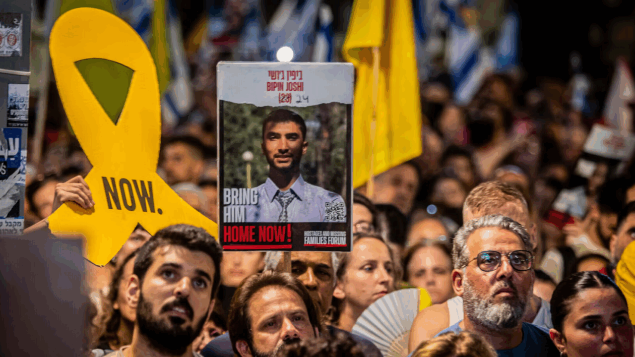 Protesters hold up signs and a placard of Bipin Joshi