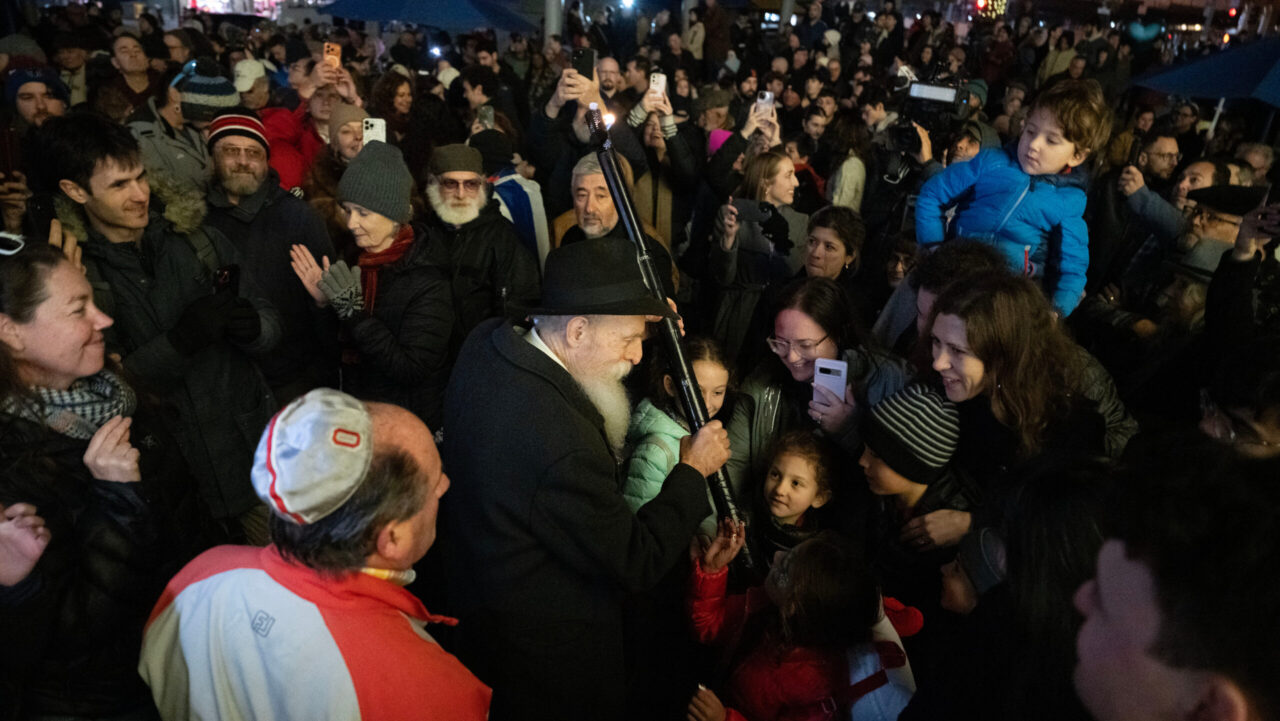 Chabad of SF Rabbi Yosef Langer carries a torch with its flame flickering as San Francisco celebrates the first night of Hanukkah at Union Square on Dec. 14. (Aaron Levy-Wolins/J. Staff)