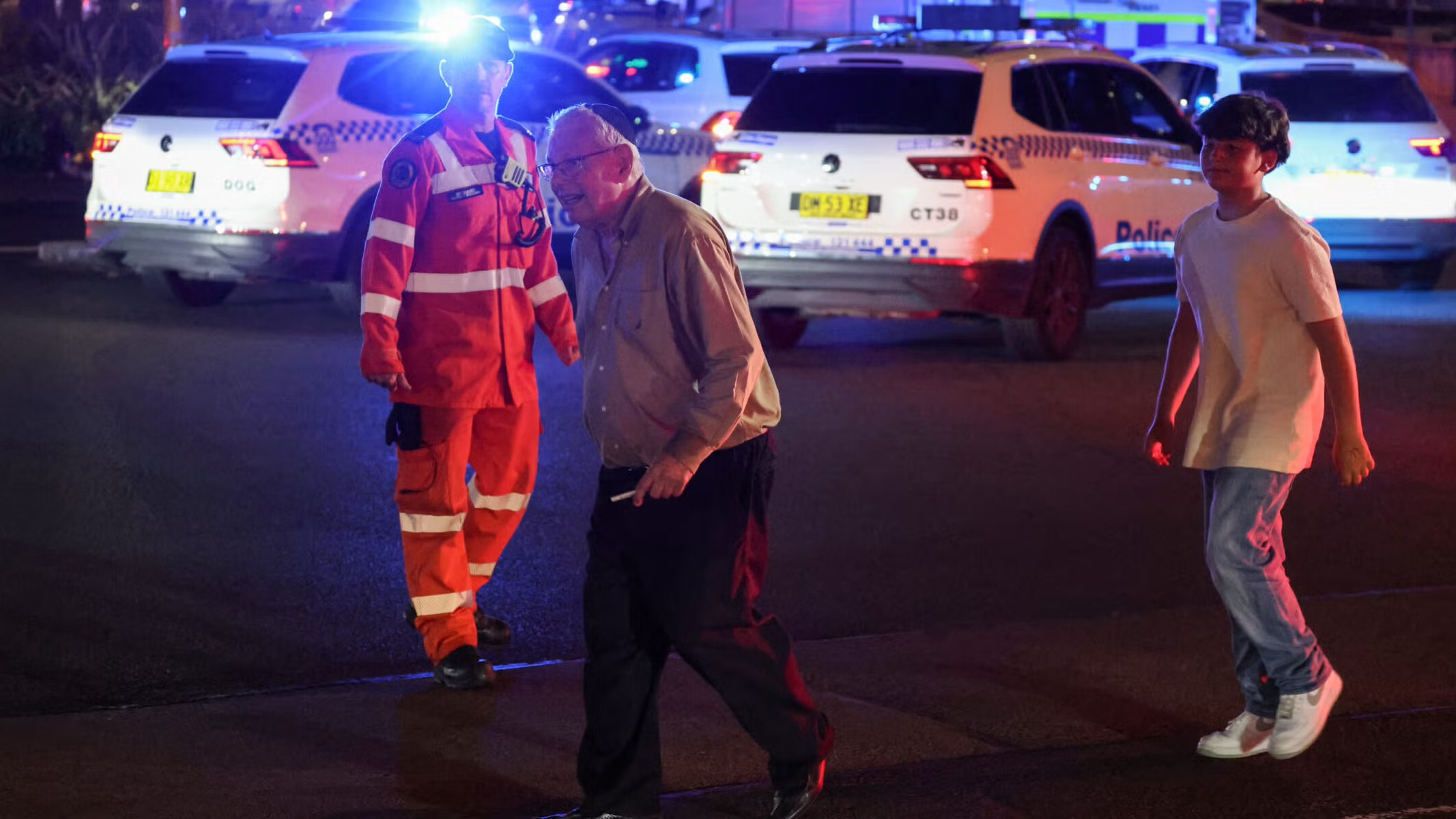 People cross a street next to police vehicles after a shooting on a Hanukkah event at Bondi Beach in Sydney, Dec. 14, 2025. (David Gray/AFP via Getty Images)