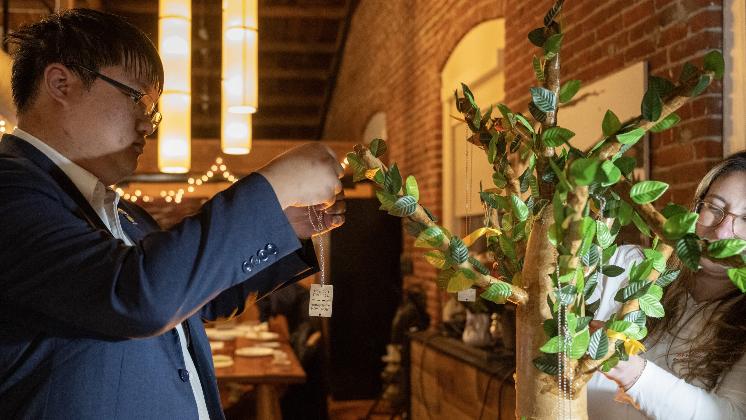 Man places necklace on paper-mache tree