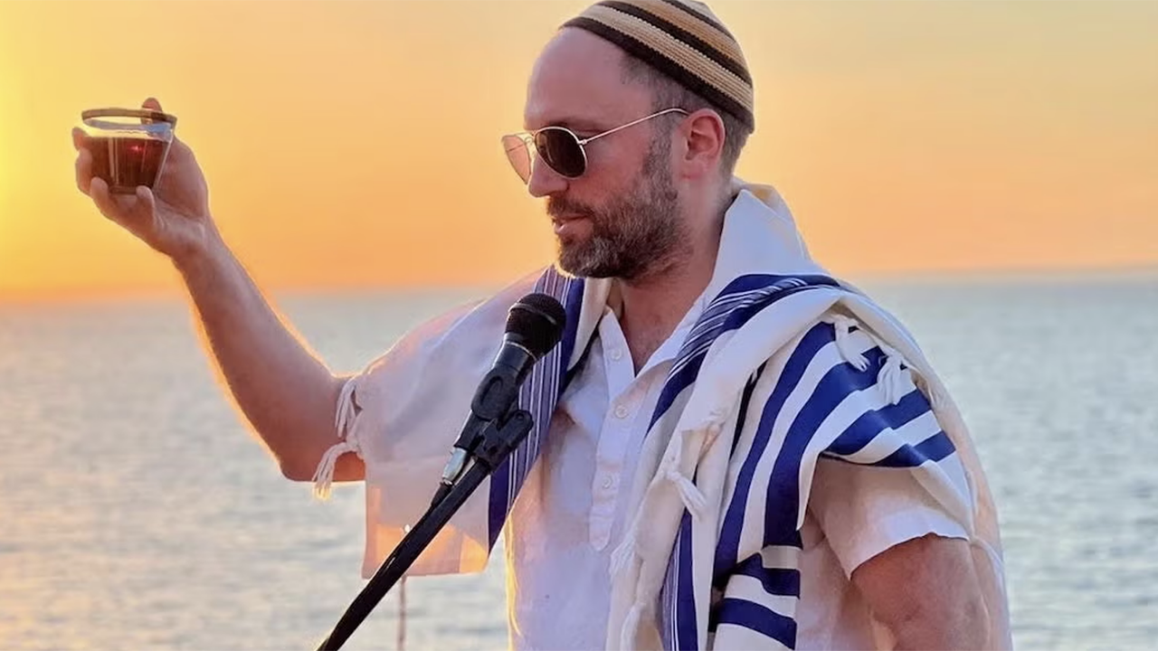 A rabbi raises a glass of kosher wine as he blesses it. (Courtesy Moti Dolgin)