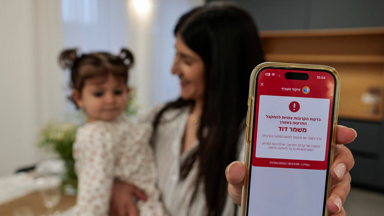 A woman shows a missile alert notification on her mobile phone as residents take cover indoors following missile fire from Iran toward Israel on the eve of the Passover, in Mishmar David, April 1. 2026. (Nati Shohat/Flash90)